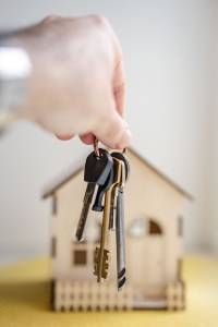 Image d'une personne tenant des clés devant une maison. Cette image illustre une opération de prêt hypothécaire In fine. 