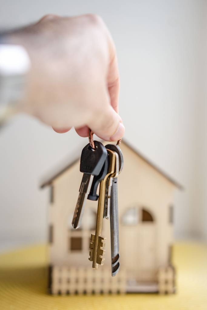 Image d'une personne tenant des clés devant une maison. Cette image illustre une opération de crédit immobilier.